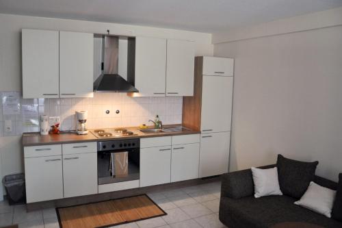 eine Küche mit weißen Schränken und einem Sofa in einem Zimmer in der Unterkunft Effelder Bürgerstube in Effeld
