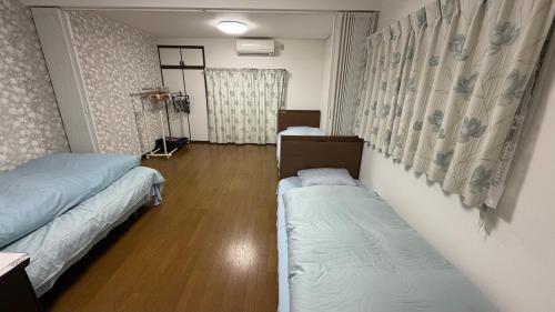 a room with two beds in a room with wooden floors at 薫樹xiang po po inn in Kyoto