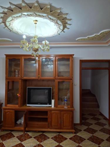 a television on a entertainment center with a chandelier at Villa abdo in Asilah