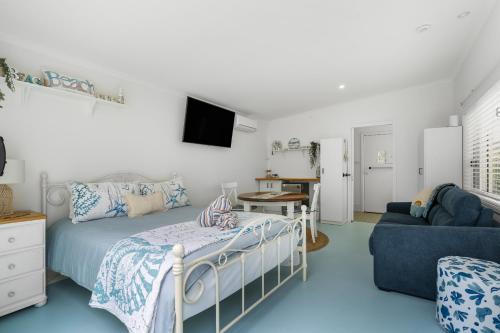 a bedroom with a bed and a tv and a couch at The Blue Cottage in Ulladulla
