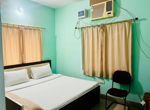 德奥加尔Alkapuri Guest House的一间卧室配有一张带风扇和椅子的床。