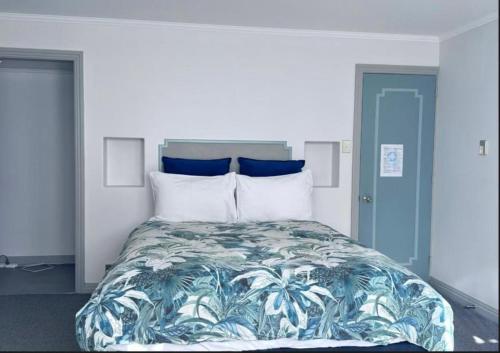 een slaapkamer met een groot bed met blauwe en witte kussens bij Pure Motel in Rotorua
