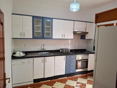a kitchen with white cabinets and a sink at Villa abdo in Asilah