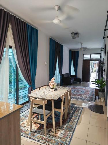 a dining room with a table and a living room at Aiman's Rose HomeStay in Teluk Panglima Garang
