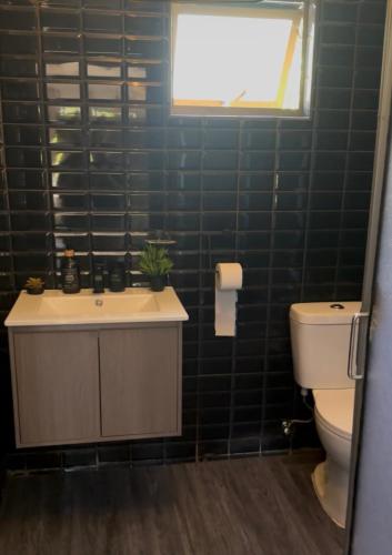 a bathroom with a sink and a toilet and a window at Quincho la Beli in Chillán