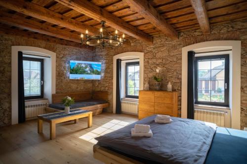 een slaapkamer met een bed, een tafel en ramen bij Liptovský mlyn in Bešeňová