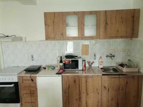 een keuken met houten kasten en een magnetron op een aanrecht bij Mala Sirena in Bukorovac