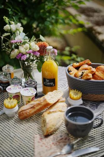 einen Tisch mit einem Korb Brot und einer Schüssel Orangensaft in der Unterkunft Château de Laforest - Les Tours in Thizy-les-Bourgs