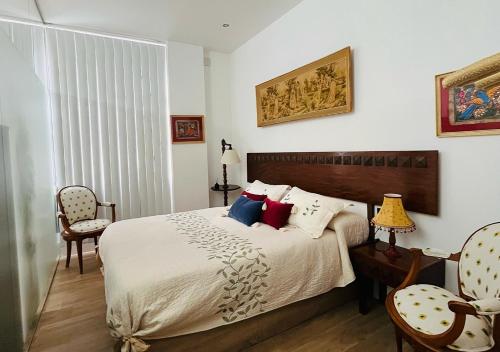 ein Schlafzimmer mit einem Bett und zwei Stühlen in der Unterkunft Estudio Vandelvira in Baeza