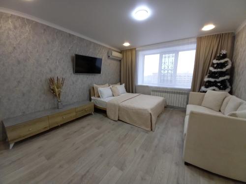 un soggiorno con letto e albero di Natale di Апартаменты в районе Космос ad Aqtöbe