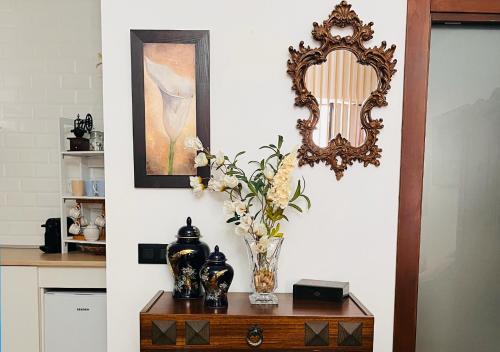eine Vase aus Blumen auf einem Tisch mit einem Spiegel in der Unterkunft Estudio Vandelvira in Baeza