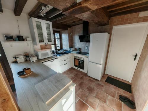 Gîte Anmany في Quarré-les-Tombes: مطبخ بخزائن بيضاء وثلاجة بيضاء