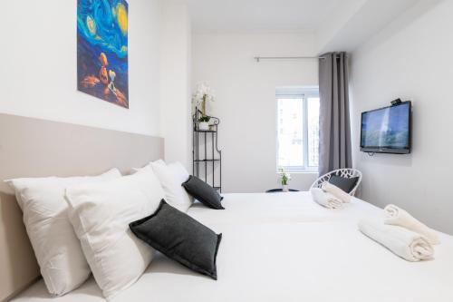 ein weißes Schlafzimmer mit einem weißen Bett mit schwarzen Kissen in der Unterkunft Da Vinci in Jerusalem