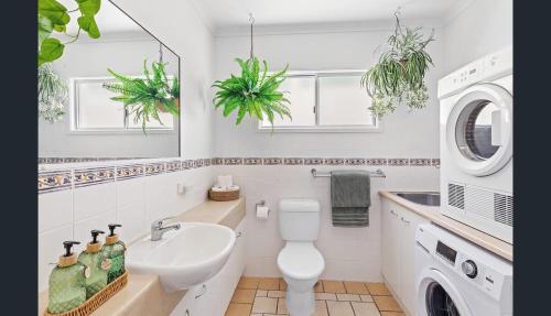 a white bathroom with a sink and a washing machine at Shingley Beach Retreat - Ocean Views Apartment in Airlie Beach