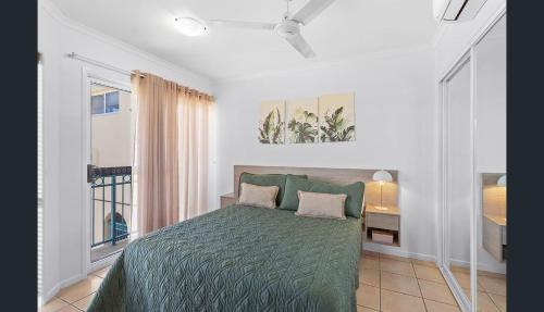 a bedroom with a green bed and a window at Shingley Beach Retreat - Ocean Views Apartment in Airlie Beach