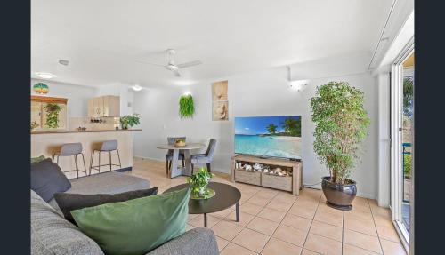 a living room with a couch and a table and a kitchen at Shingley Beach Retreat - Ocean Views Apartment in Airlie Beach