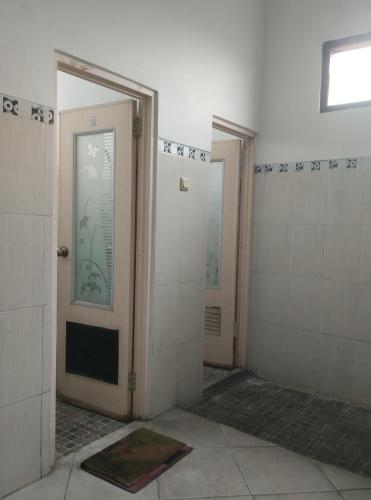 a bathroom with two doors and a tile wall at AN homestay2 Syariah in Wonosobo