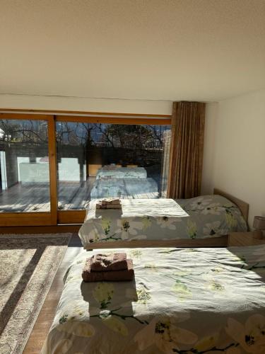 una camera con tre letti e una grande finestra di Chalet à Savièse en bordure de forêt a Savièse