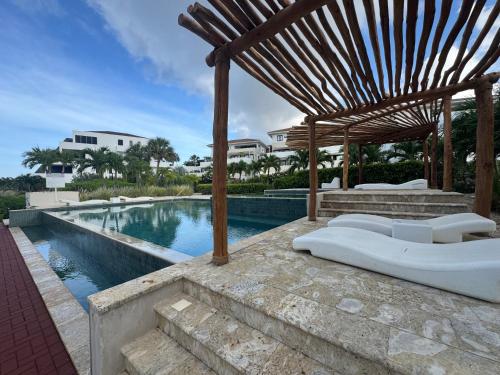 een zwembad met een houten pergola naast een zwembad bij Blauw Geluk I - At Blue Bay Curaçao in Blauw Baai