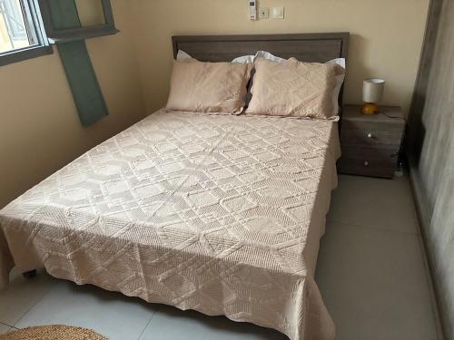 a bed with a white comforter and a night stand at Maison indépendante avec jardin in Abidjan