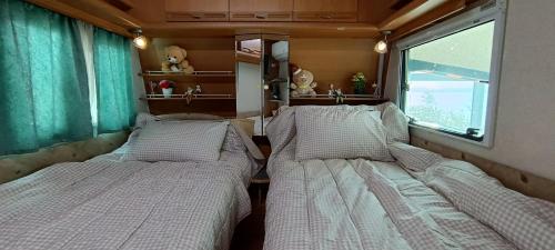 two beds in a small room with a window at 노을이 아름다운 호미곶 캠핑카 in Sup'sil
