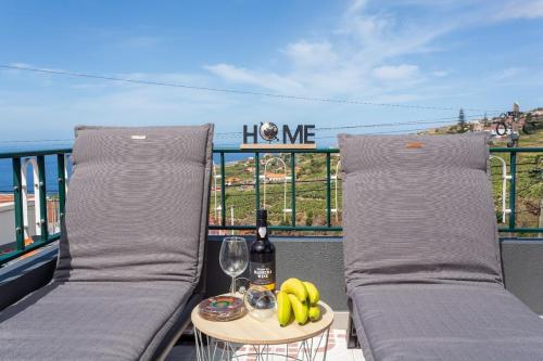 a balcony with two beds and a table with a glass of wine and bananas at Estrela House I Calheta Madeira in Calheta