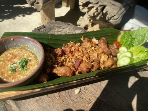 a plate of food on a banana leaf with a bowl of soup at Amazing Mountain Camping, Bar&Grill in Ban Pang Hai