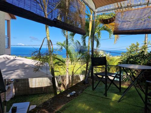 eine Terrasse mit Tisch und Stuhl und dem Meer in der Unterkunft Petit jardin suspendu in Petite Île