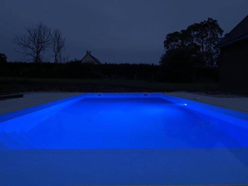 - une piscine bleue dans une cour la nuit dans l'établissement 4 minutes from Sainte-Mère-Église - Independent apartment on first floor of big house with garden and heated pool opened if weather is ok, à Fresville