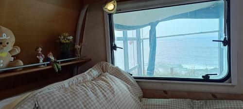 a bedroom with a window with a view of the ocean at 노을이 아름다운 호미곶 캠핑카 in Sup'sil
