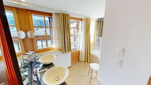 een badkamer met 2 wastafels en 2 ramen bij Schweizerhaus Swiss Quality Hotel in Maloja