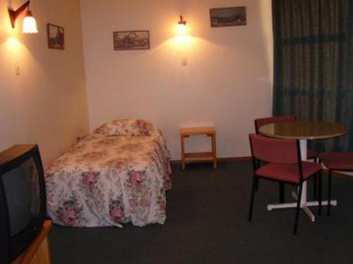 a hotel room with a bed and a table and a tv at Motel Six in Hamilton