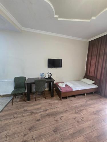 een kamer met een bed, een bureau en een tv bij MAHALI HOTEL in Batoemi