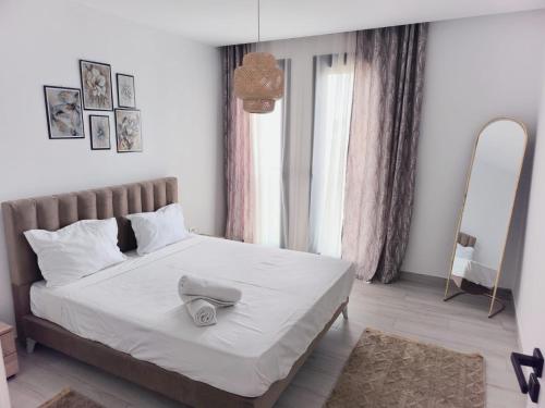 ein Schlafzimmer mit einem weißen Bett mit Hut darauf in der Unterkunft Jade Luxury Apartment La Marsa in Dar el Haj Ahmed Souid