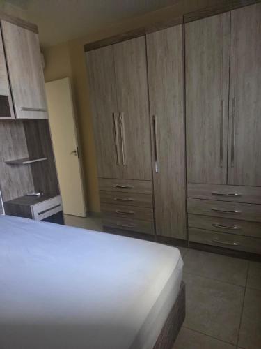 een slaapkamer met houten kasten en een wit bed bij Beachfront Apartment in Itanhaém