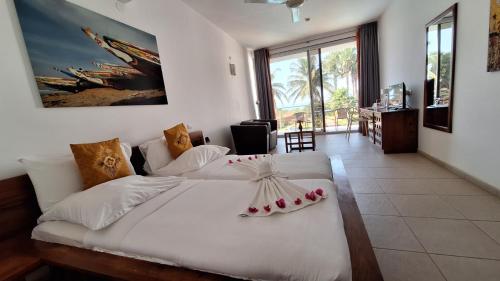 een slaapkamer met een groot wit bed met bloemen erop bij Leo's Beach Hotel - Adults Only in Brufut