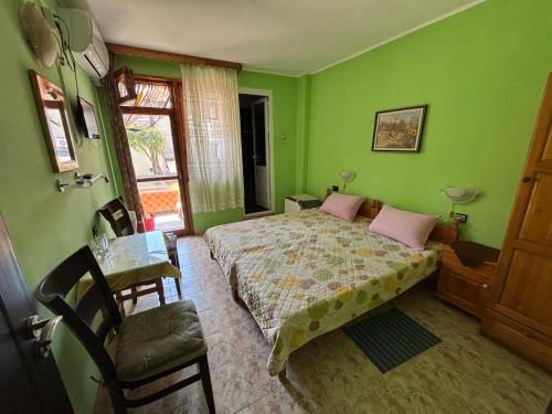 a bedroom with green walls and a bed with pink pillows at Dom Lidiya in Pomorie