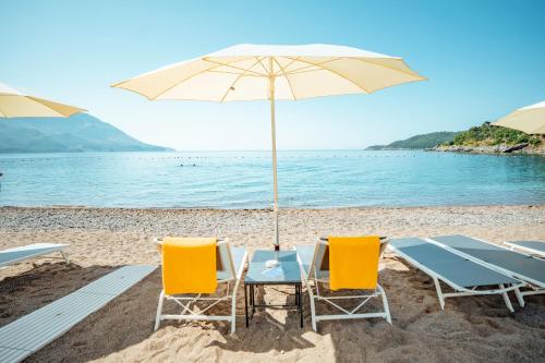 een tafel en stoelen met een parasol op een strand bij Hotel Harmonia by Dukley in Budva