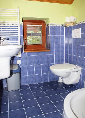 a blue tiled bathroom with a toilet and a sink at Chata Dominika - Tále in Bystrá