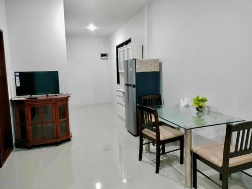 ein Esszimmer mit Tisch und Fernseher in der Unterkunft ปารมีฟาร์มสเตย์ in Ban Chao Nam
