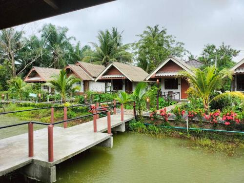 eine Häuserreihe mit einer Brücke über einen Fluss in der Unterkunft ปารมีฟาร์มสเตย์ in Ban Chao Nam