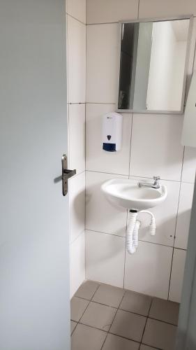 een witte badkamer met een wastafel en een spiegel bij Hotel leo in Pelotas