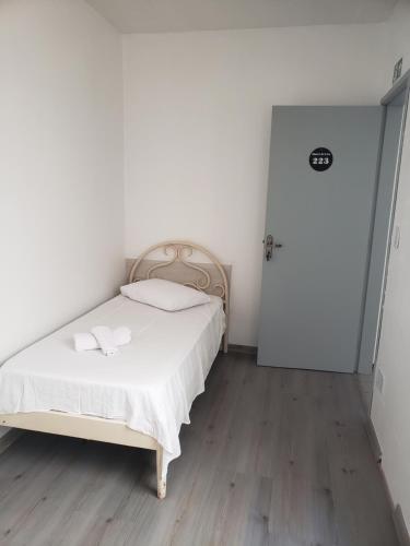 een slaapkamer met een bed met witte lakens en een houten vloer bij Hotel leo in Pelotas