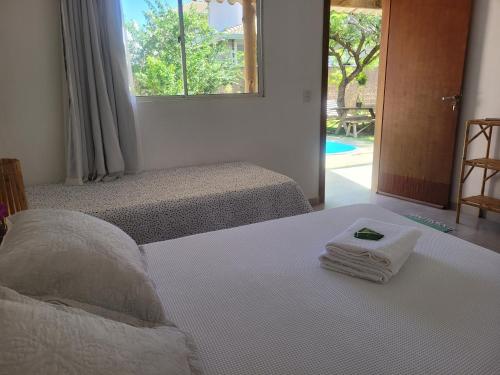 1 Schlafzimmer mit 2 Betten, Handtüchern und einem Fenster in der Unterkunft Pousada Canto das Estrelas in Chapada dos Guimarães