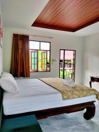 a bedroom with a large bed and windows at ปารมีฟาร์มสเตย์ in Ban Chao Nam