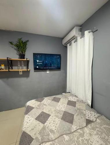 a bedroom with a bed and a tv on the wall at Quarto Privado Próximo as Praias de Itajaí in Itajaí