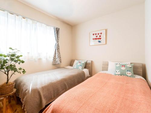 a bedroom with two beds and a window at tazuraya-suehiro-一棟貸切-無料駐車場 in Takamatsu