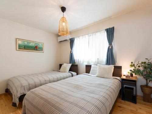 two beds in a bedroom with blue curtains at tazuraya-suehiro-一棟貸切-無料駐車場 in Takamatsu