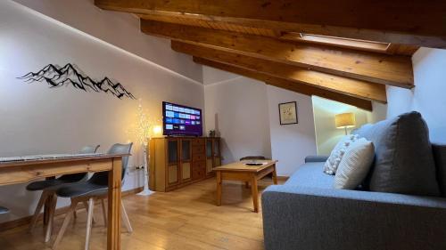 een woonkamer met een blauwe bank en een bureau bij Casa La Muga in Benasque