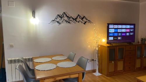 een eetkamer met een tafel met stoelen en een televisie bij Casa La Muga in Benasque